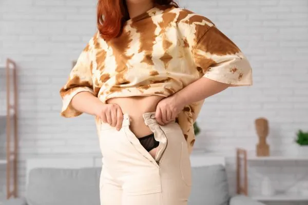 Image of woman trying to do her trousers up after pregnancy weight gain Faringdon